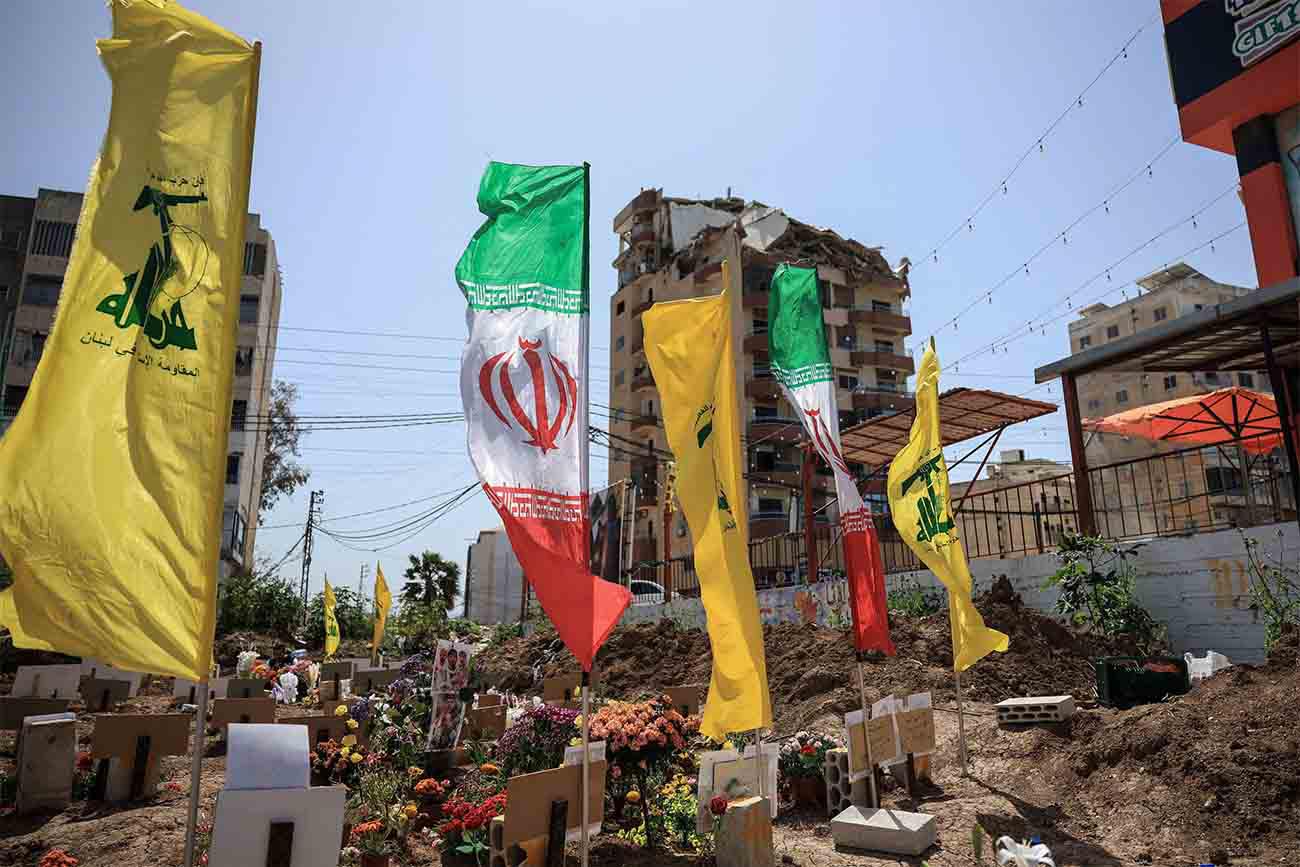 Hezbollah and Iranian flags flutter at a temporary graveyard by a damaged building in Tyre, south Lebanon